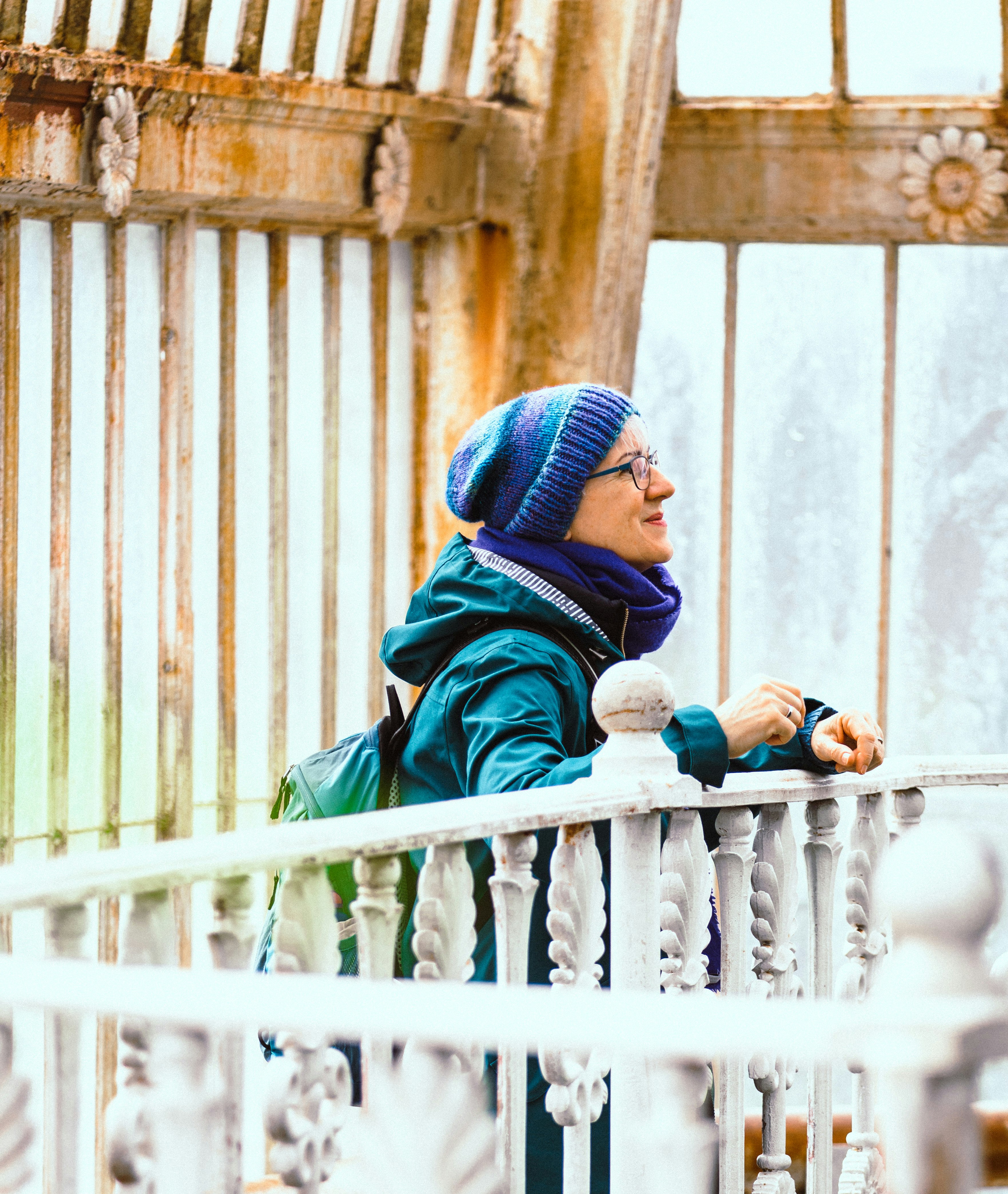 person in blue and black hoodie and blue knit cap sitting on white wooden fence during